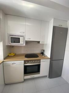 a kitchen with white cabinets and a stove and a microwave at APARTAMENTO TURIETO (BROTO-ORDESA) in Broto