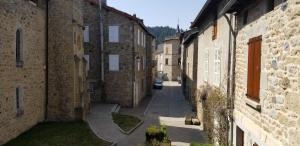 un callejón con edificios de piedra y un coche en la distancia en Le gîte des remparts au cœur du village médiéval en Le Malzieu-Ville