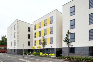 two white buildings with yellow windows on a street at Yugo Explore - Arofan House in Cardiff