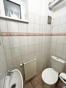 a white bathroom with a toilet and a window at Dunai Panorámás Apartman Dunaszentmiklóson in Dunaszentmiklós