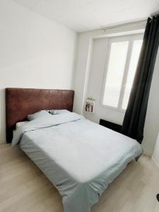 - une chambre avec un lit doté de draps blancs et une fenêtre dans l'établissement 701 Studio à proximité du métro et des commerces, à Bagnolet