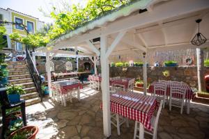 un patio con mesas y sillas bajo una sombrilla blanca en Ebruli Hotel en Bozcaada