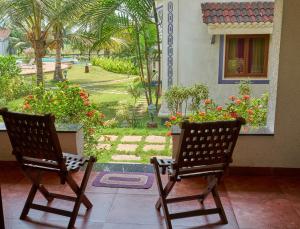 two chairs sitting on a porch looking out at a garden at Riviera Sapphire in Siolim