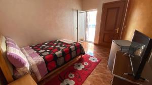 een kleine kamer met een bed en een rood tapijt bij Kompleksi GJONI in Fier