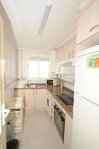 a white kitchen with a sink and a refrigerator at PLAYASOL Orangecosta 1 dormitorio in Benicàssim