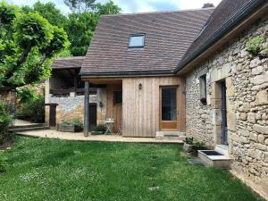 a stone house with a wooden door and a yard at La Grenaderie in Sergeac