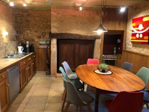 a kitchen with a wooden table and chairs at La Grenaderie in Sergeac