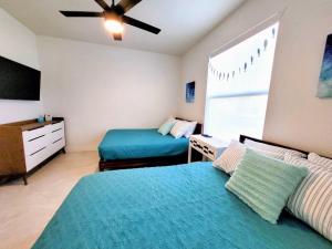 a bedroom with two beds and a ceiling fan at Blue Door Retreat - Luxury Pool Home - sleeps 8 in Cape Coral
