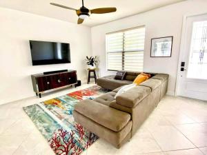 ein Wohnzimmer mit einem Sofa und einem Flachbild-TV in der Unterkunft Blue Door Retreat - Luxury Pool Home - sleeps 8 in Cape Coral