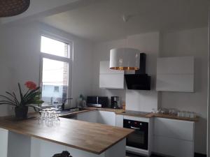 a kitchen with white cabinets and a wooden counter top at Veronique schouckens in Binche +11 photos
