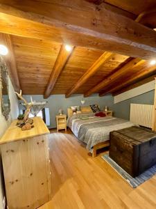 una grande camera da letto con letto e soffitti in legno di Appartamento la Torre Vinadio a Vinadio