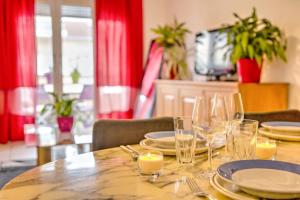 a wooden table with plates and glasses on it at Le Jardin de l'Atrium - Appartement moderne proche de Genève et Palexpo in Saint-Julien-en-Genevois