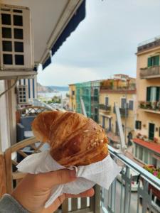 a person is holding a pastry on a balcony at A Casa dei Bruno B&B in Pozzuoli