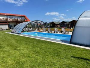 a swimming pool with chairs and a building at Lazur in Sarbinowo