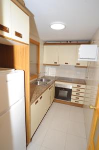 uma cozinha com armários brancos, um lavatório e um frigorífico em MADEIRA Orangecosta 1 dormitorio em Benicàssim
