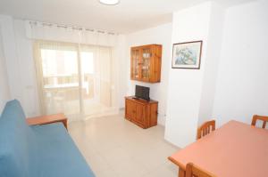 uma sala de estar com uma mesa e uma televisão na parede em MADEIRA Orangecosta 1 dormitorio em Benicàssim