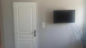 einen Flachbild-TV an einer Wand neben einer Tür in der Unterkunft Studio chaleureux vue sur le massif du vercors . in Alixan