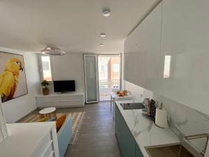 a kitchen with white counters and a yellow bird on the wall at AMBER APARTMENTS - SUNNY STUDIO in Morro del Jable