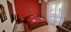 1 dormitorio con cama y pared roja en Casa Lucia en Siracusa