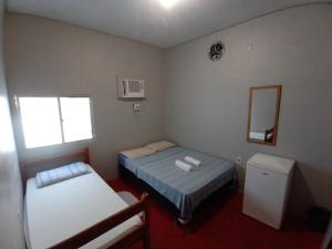 Habitación pequeña con 2 camas y espejo. en Discovery hostel en Manaos
