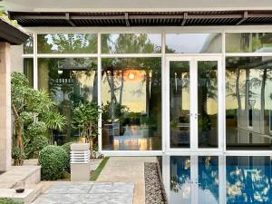 une maison en verre avec une piscine dans la cour dans l'établissement Sunset Ocean Front Villa , Mai Khao Phuket, à Mai Khao Beach