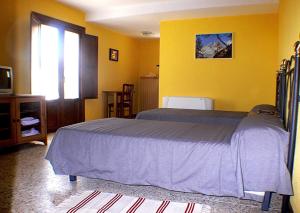 1 dormitorio con cama y pared amarilla en Casa Lino Huesca, en Chibluco