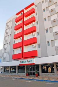 a hotel building with a red and white facade at Habitat Hotel de Leme Ltda in Leme