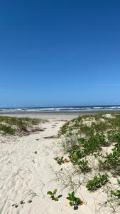 a sandy beach with grass and plants on it at Apartamento Boqueirão Ilha Comprida Tati Ortega in Ilha Comprida