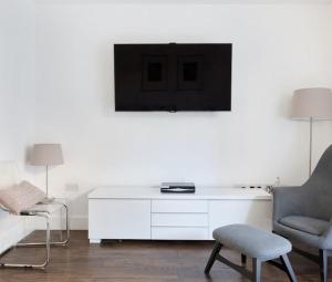 a white living room with a chair and a tv at Tower Bridge Lux-Townhouse in London