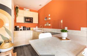 une cuisine orange avec un évier et un comptoir dans l'établissement Le 102, Maison avec Terrasse et parking Gare de ROUEN, à Rouen