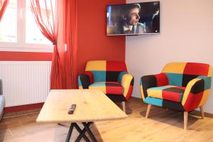 een kamer met 2 stoelen, een tafel en een tv bij Gîte les Eglantines Rez-de-Jardin in Gérardmer