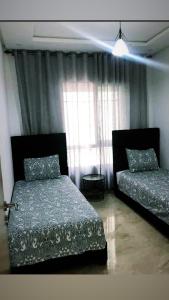 Un dormitorio con dos camas y una ventana. en Magnifique Appartement balnéaire à Bouznika avec piscine, en Bouznika 14 fotos más