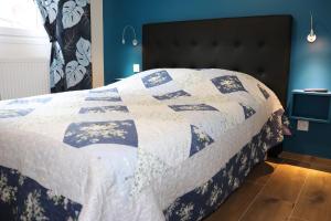een bed met een blauwe en witte quilt bij Gîte les Eglantines Rez-de-Jardin in Gérardmer
