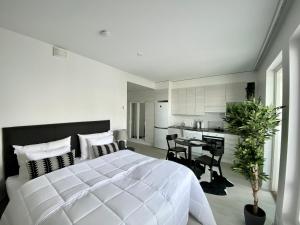 a white bedroom with a large bed and a kitchen at Borg Travel Center in Pori