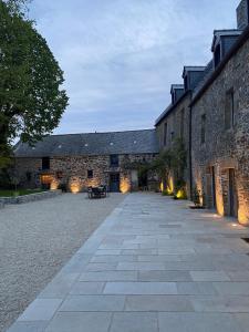 a courtyard of a stone building with a sidewalk at La Seigneurie des Ondes in Saint-Benoît-des-Ondes