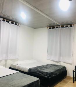 CajamarcaにあるMIRADOR DE LA ARCADIAのベッドルーム1室(ベッド2台、白いカーテン付)