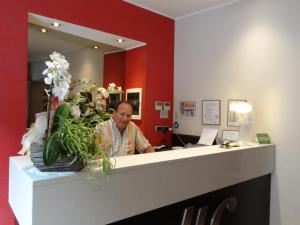 a man sitting at a reception desk in a salon at Hotel Castelletto in Milan