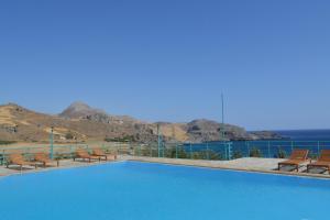 a swimming pool with benches and mountains in the background at Sokol Resort in Damnoni