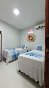 1 dormitorio con 2 camas y un sombrero en la pared en Studio pé na areia com 2 quartos sala cozinha en Trairi