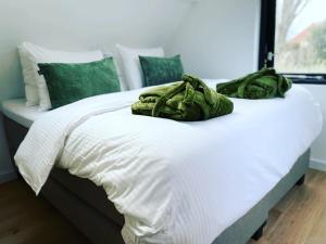 a bed with green pillows on top of it at Ambiance in Hollum