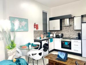a kitchen with white cabinets and a table with chairs at Kunda House Moseley Apartments in Birmingham