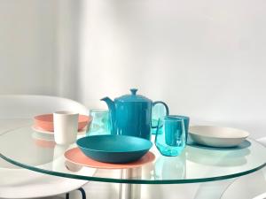 a glass table with a blue pitcher and dishes on it at Kunda House Moseley Apartments in Birmingham