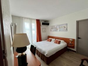 a hotel room with a bed and a lamp at Hotel Colbert in Saint-Jean-de-Luz