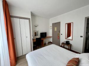 a bedroom with a white bed and a desk at Hotel Colbert in Saint-Jean-de-Luz