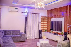 a living room with a couch and a tv at Luxury 3-Bedroom Duplex FAST WIFI & 247Power in Lagos