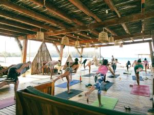 un grupo de personas haciendo yoga en una terraza de madera en Selina Playa Venao en Playa Venao