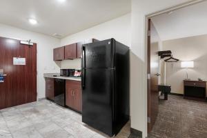 a black refrigerator in a kitchen with wooden cabinets at Cobblestone Hotel & Suites - Urbana in Urbana