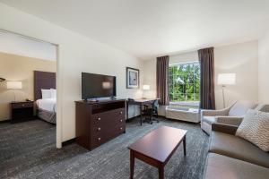 a hotel room with a bed and a living room at Cobblestone Hotel & Suites - Urbana in Urbana