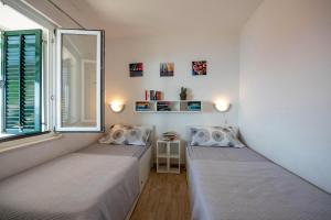 two beds in a room with a window at Apartment Zora in Trogir