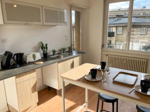 una cucina con bancone, tavolo e finestra di Chambres privées -Private room- dans un spacieux appartement - 100m2 centre proche gare a Mulhouse